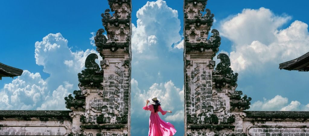 Young woman standing in temple gates at Lempuyang Luhur temple in Bali, Indonesia. Vintage tone.