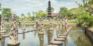 Happy tourist at Tirtagangga water palace with fountains and ponds on Bali, Indonesia